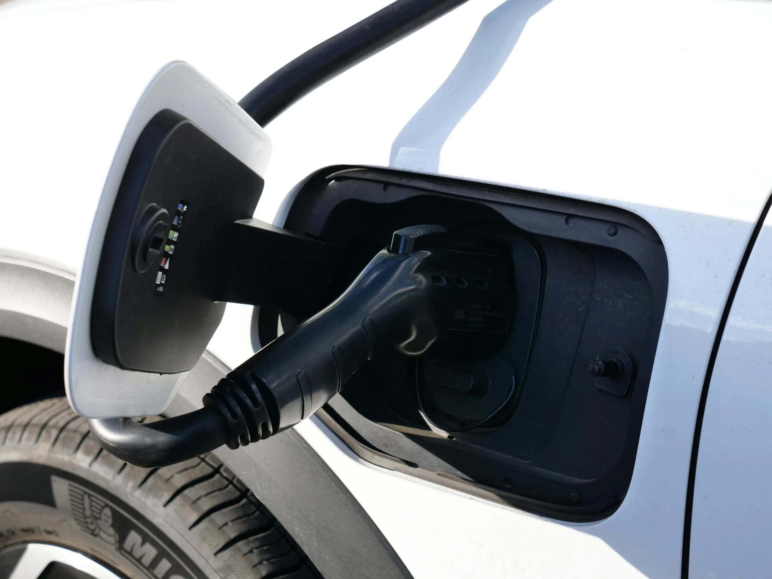 Close-up view of an electric vehicle charging with a focus on the connector and charging port.
